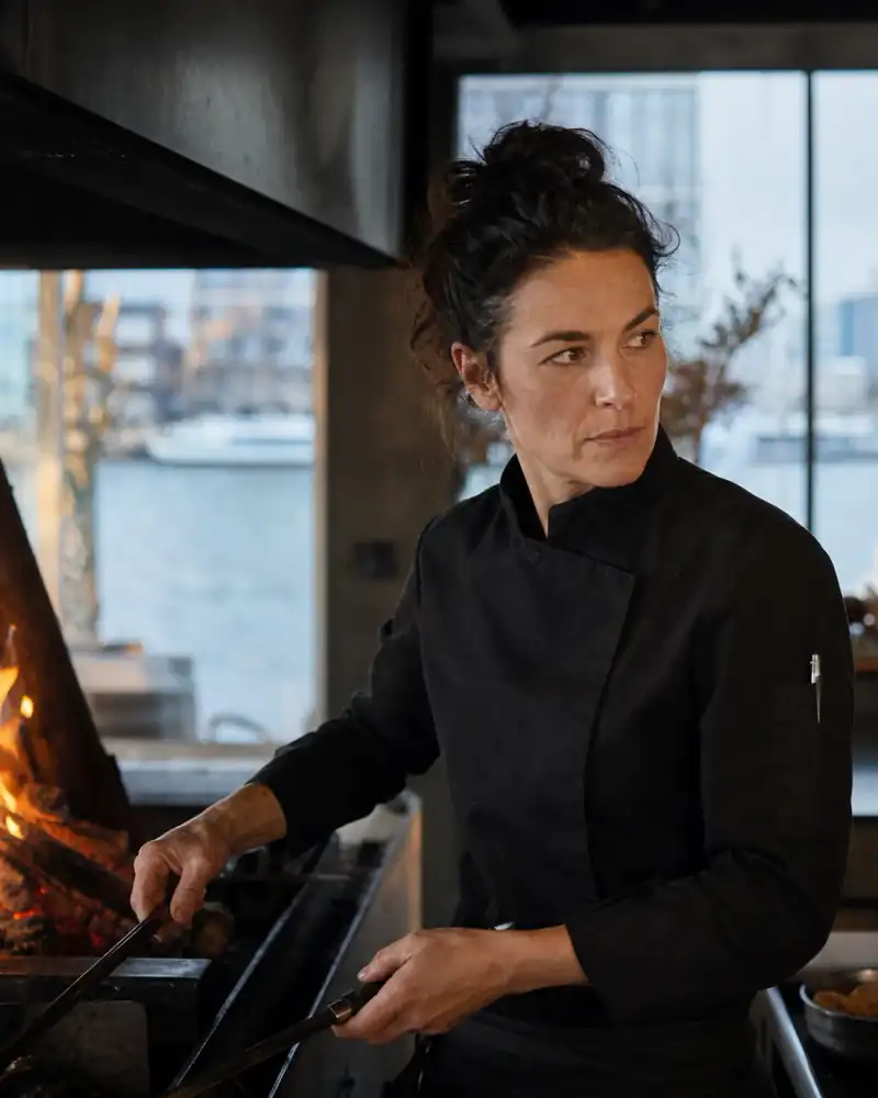 Chef werkt geconcentreerd naast het open vuur.